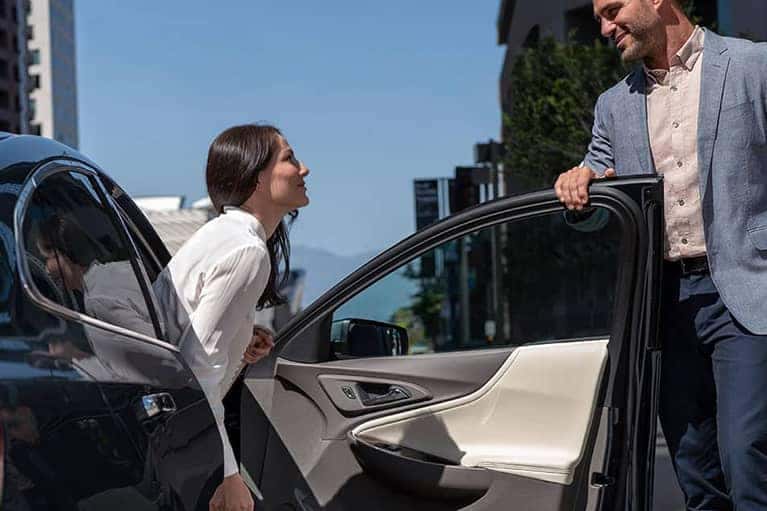 Male in a blazer opens the passenger door for a female to exit.