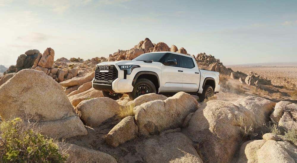 A white 2022 Toyota Tundra TRD Pro CrewMax is shown off-roading on rocks.