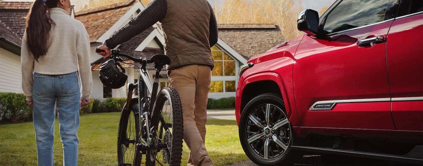 A family is shown next to a red 2023 Toyota Sequoia Capstone.