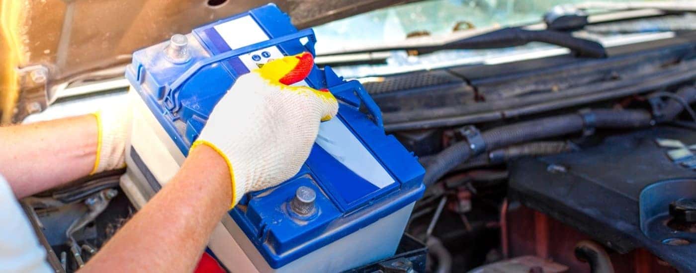 A mechanic is shown replacing a battery.