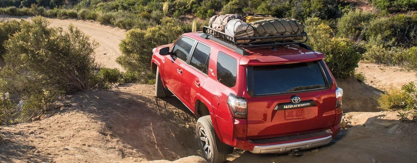 A red 2022 Toyota 4Runner is shown from the rear driving over large rocks.
