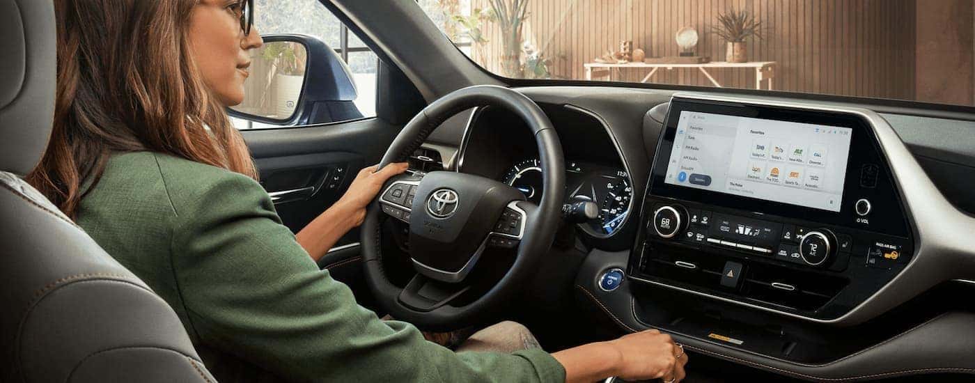 A woman is shown driving a 2023 Toyota Highlander Hybrid.