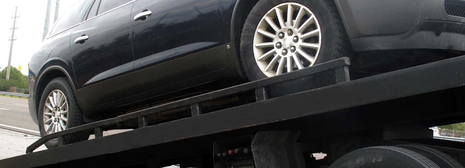 A black car being towed on a flatbed tow truck