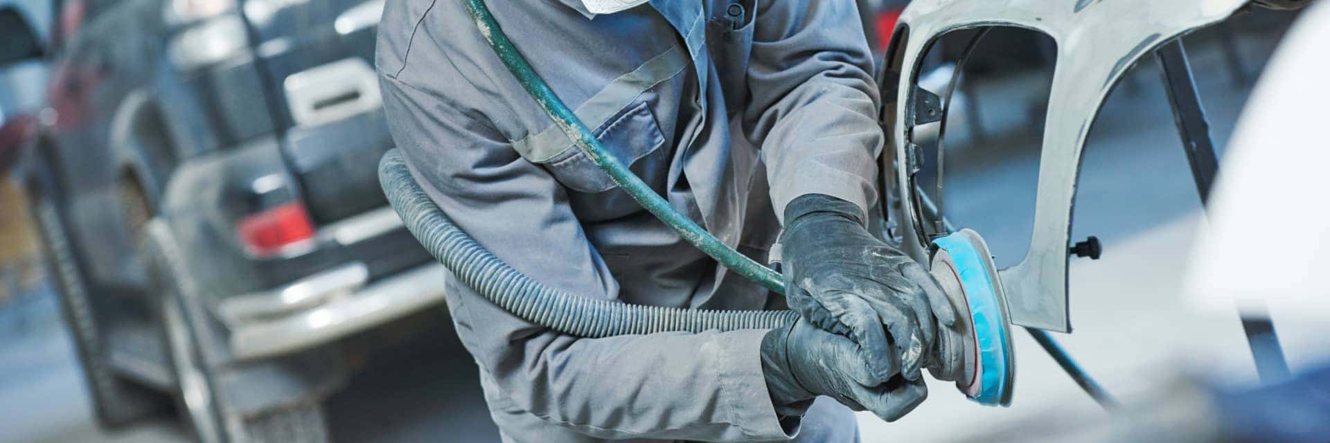Body Shop technician grinding the hood of a vehicle