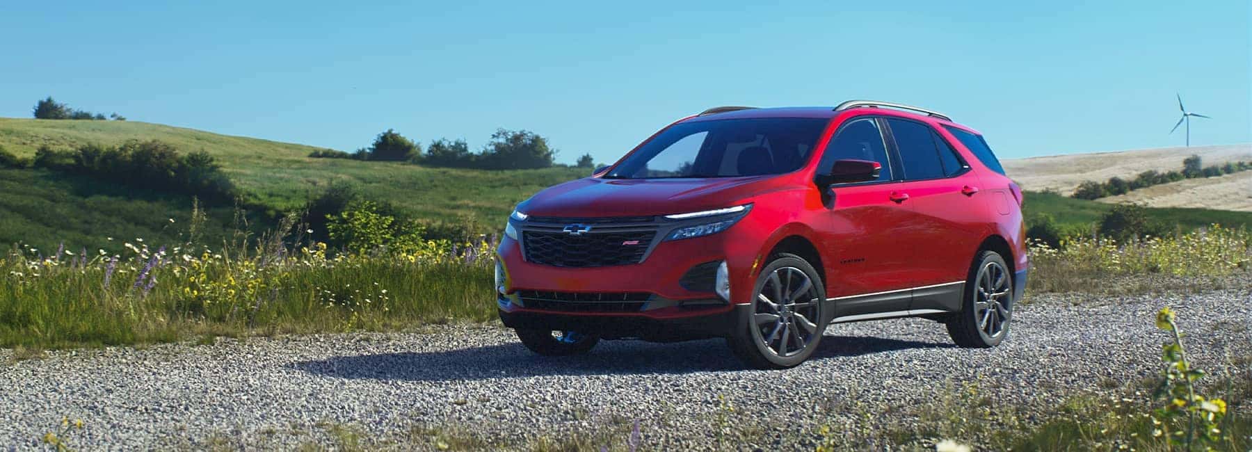 2023 Red Chevrolet Equinox parked on a gravel road in a field