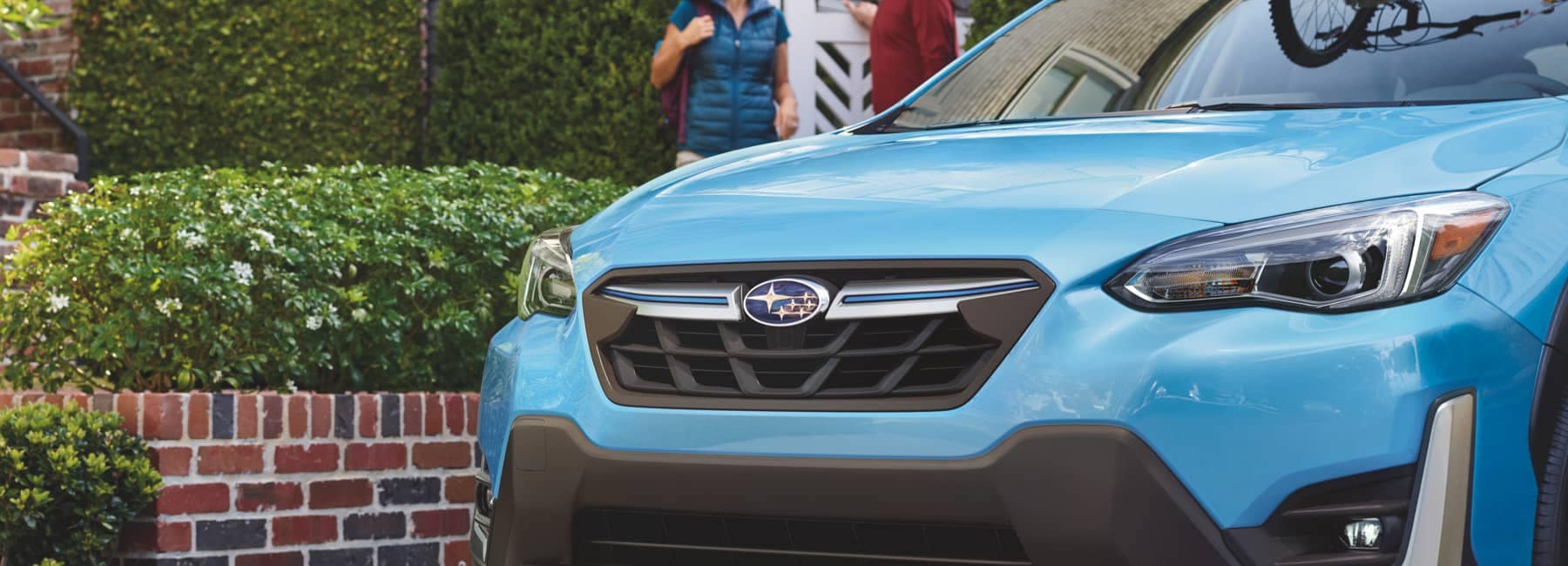 2022 Subaru Crosstrek Hybrid with bicycles mounted on top and parked in front of brick house