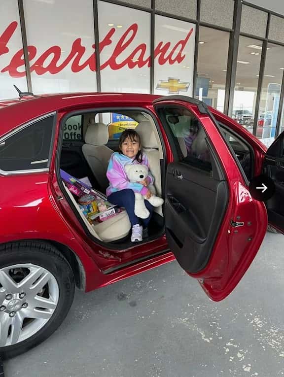 girl holding bear with car door open