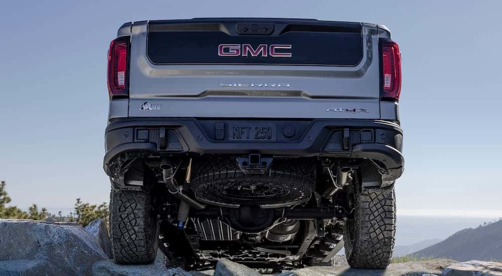 A silver 2025 GMC Sierra AT4x AEV from the rear at a low angle.