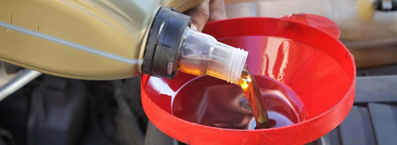 technician pouring oil into car engine