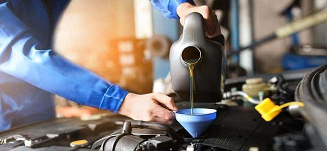 A service technician putting oil into an engine