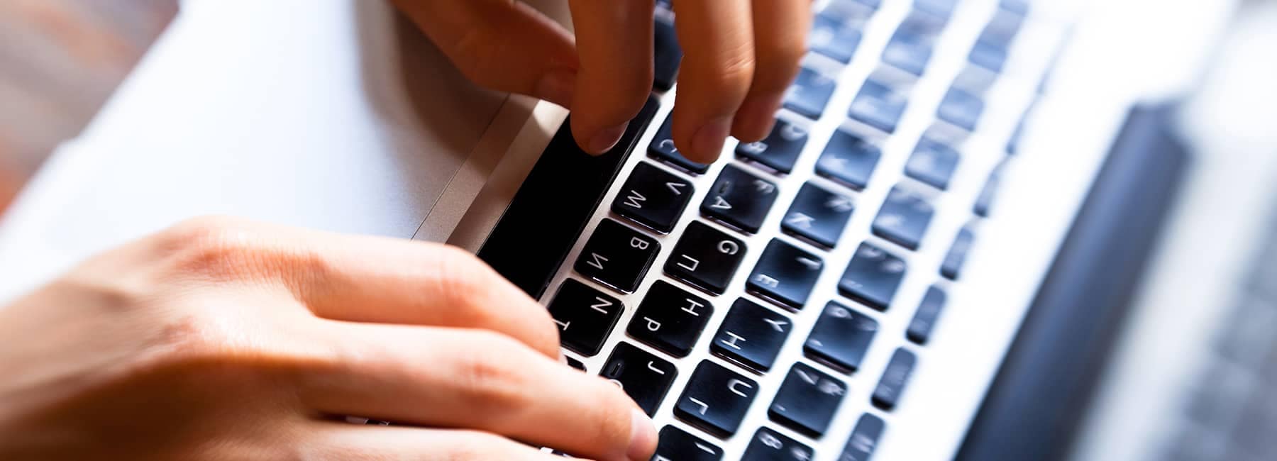 A closeup image of a person typing on a laptop keyboard
