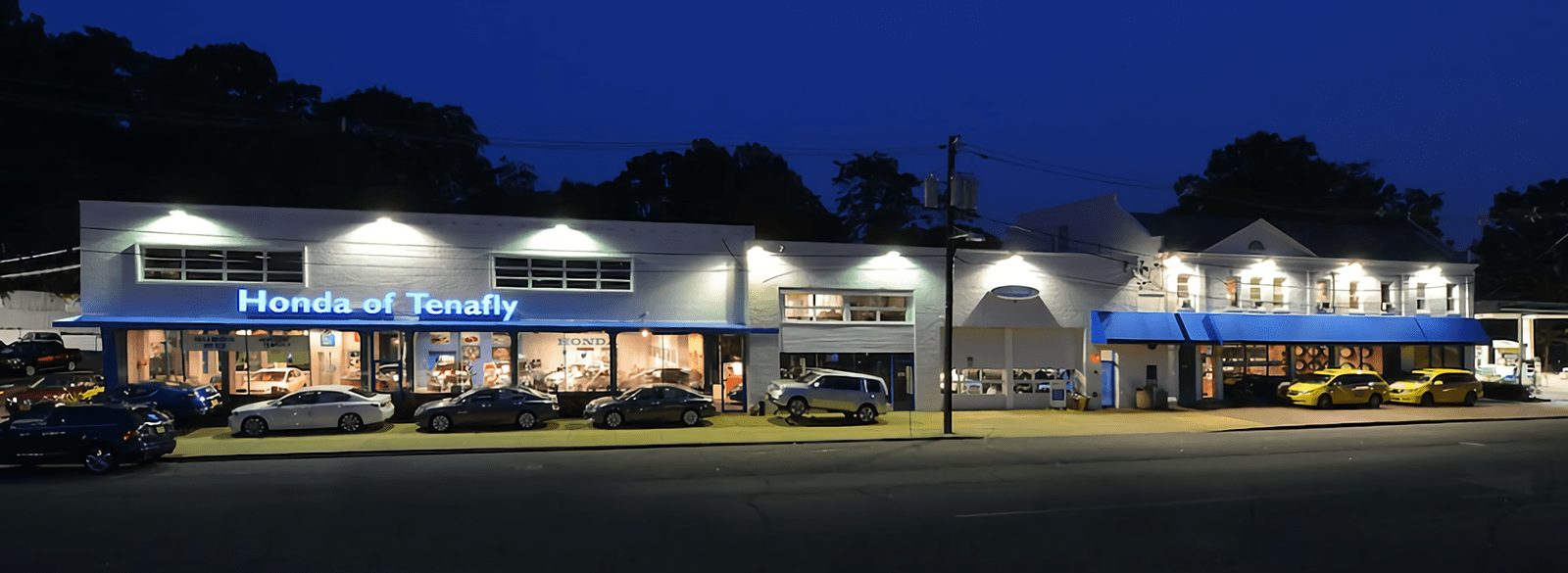 An exterior shot of a Honda dealership at night.