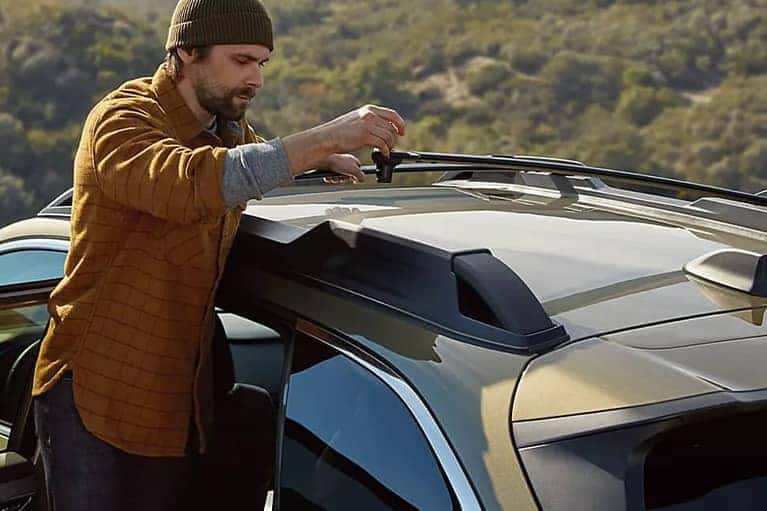 2022 Subaru Outback- man rearranging track bars on car-valley background-green_mobile