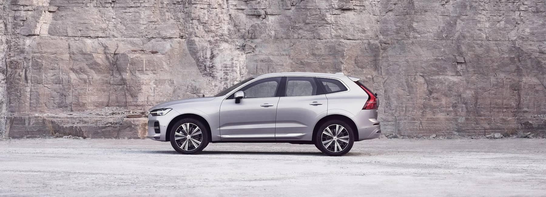 A silver Volvo XC60 standing still in front of a rock wall