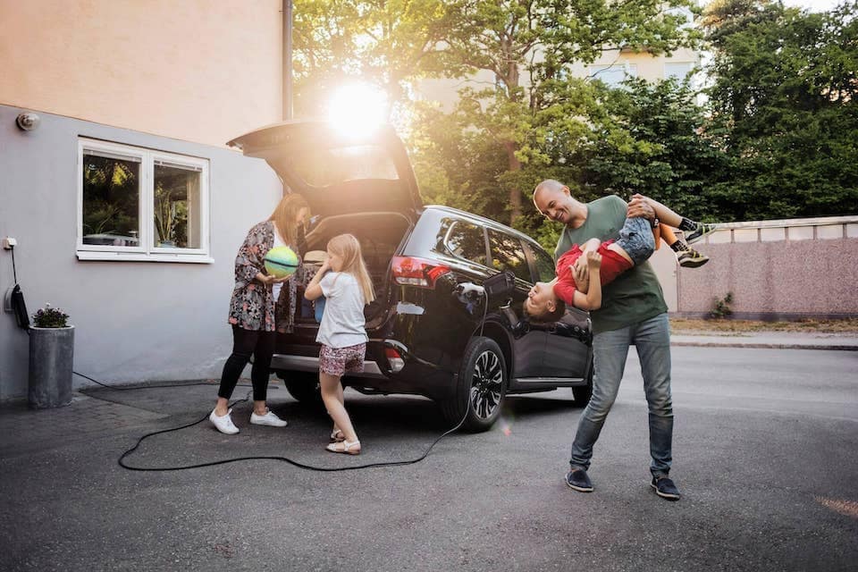 Family hanging around their EV charging vehicle