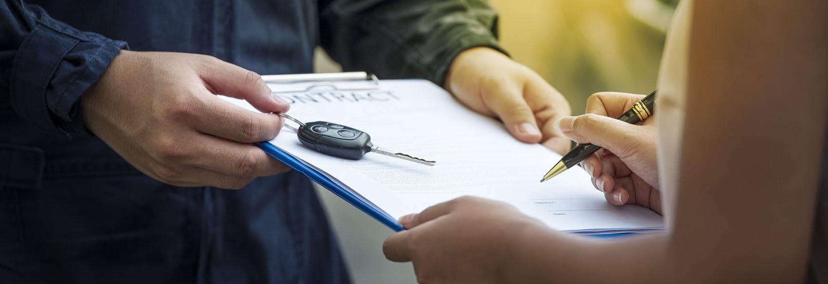 An up close shot of someone signing lease papers while one of our employees hands them the keys to their new car! Learn more about leases like how long a car lease is here.