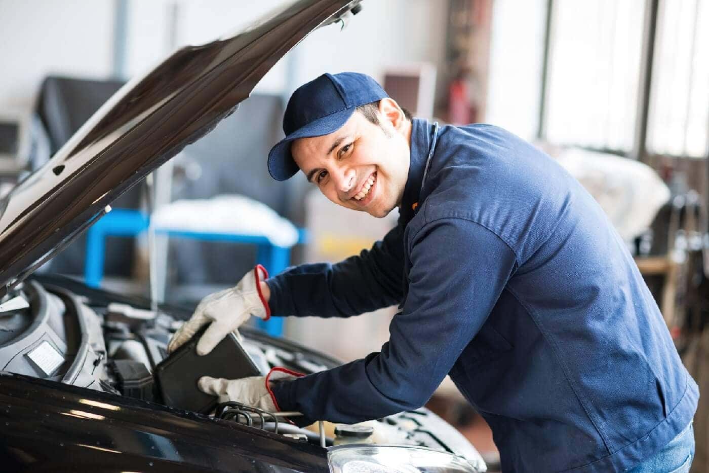Smiling mechanic working on car