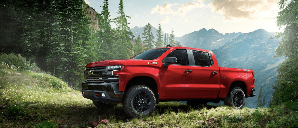 2019 Chevy Silverado 1500 in red parked in field by mountain
