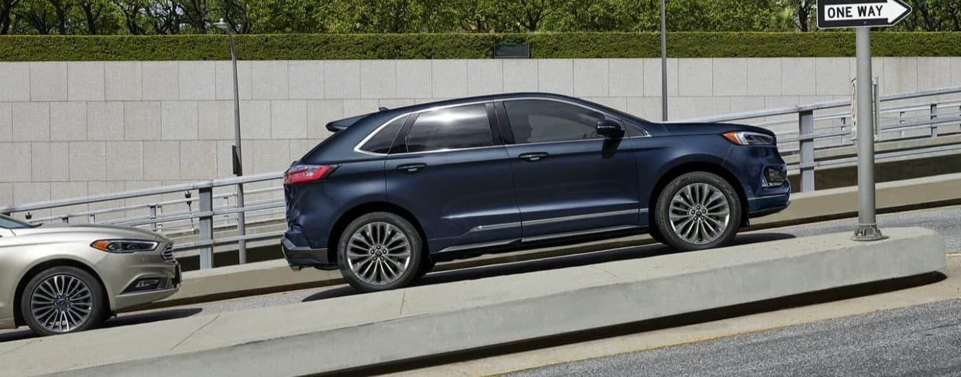 A dark blue 2023 Ford Edge is shown driving up a hill after leaving a Ford Dealer in Atlanta, GA.