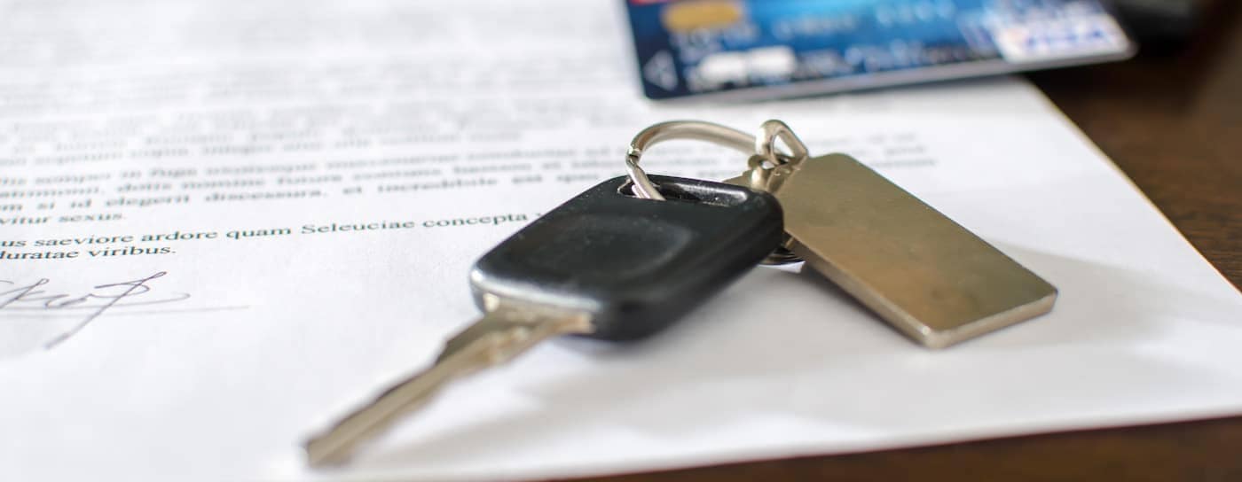 Car keys and a credit card on top of a signed car loan