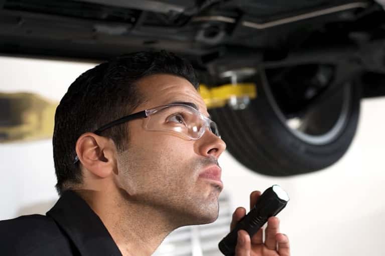 GM-technician-examines-under-car-body-in-service-bay