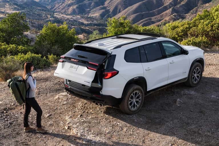 2026-GMC-Acadia-parked-on-dirt-road-woman-with-backpack
