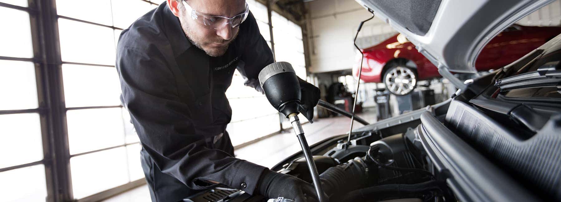 GM-service-technician-reading-from-a-tube-inserted-into-engine
