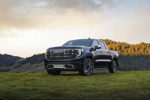 GMC-truck-parked-on-grassy-hills-with-sun-shining-on-the-hood