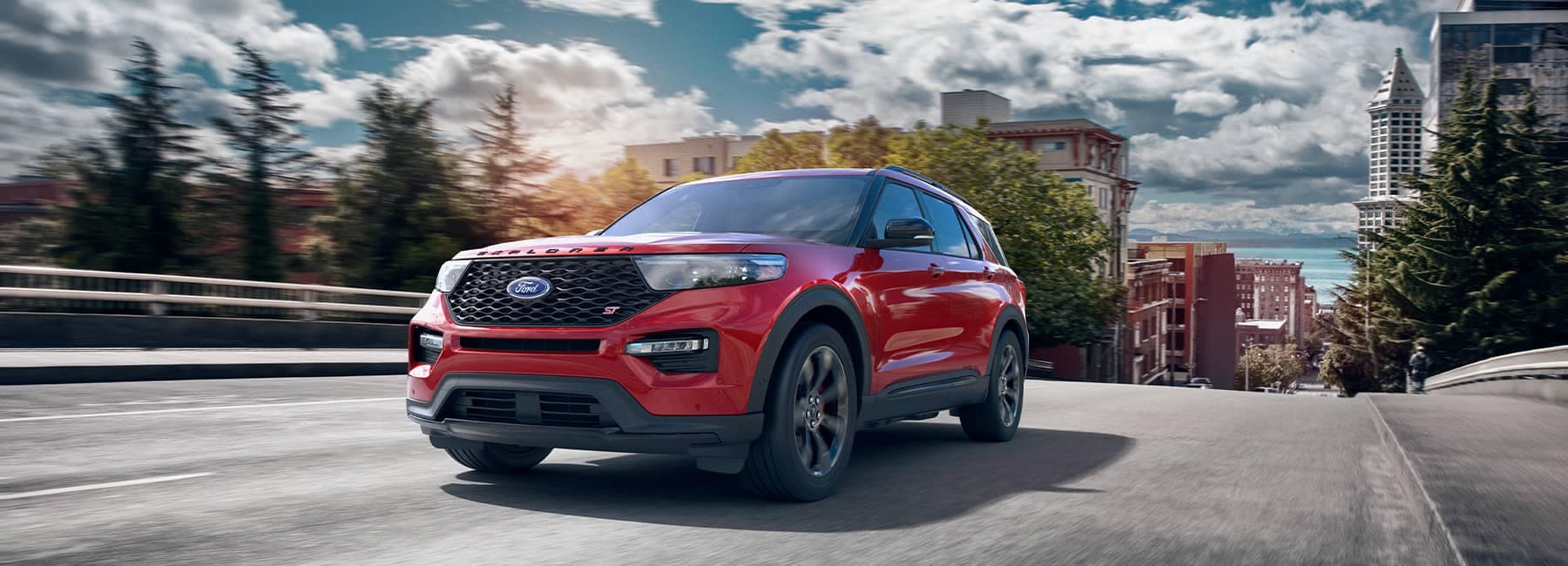 Red 2021 Ford Explorer driving up a hill out of a city