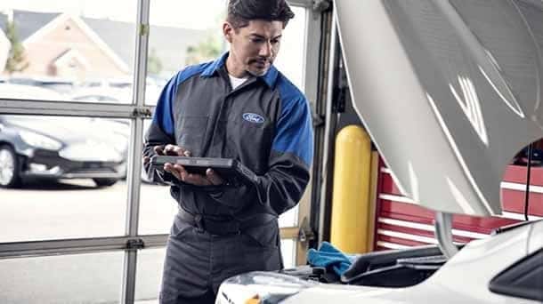 Ford technician examines car engine