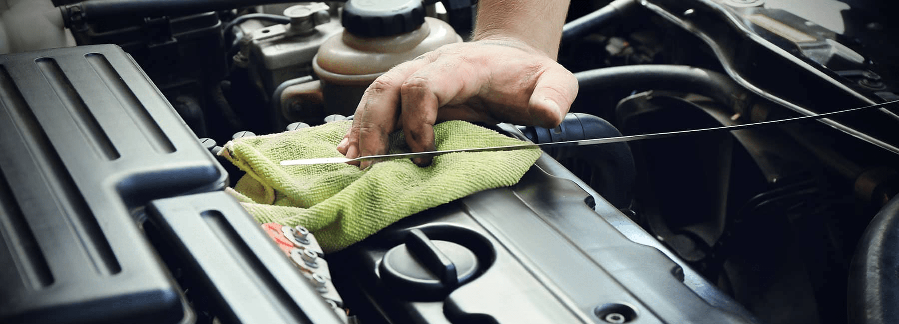 technician checks oil level in car engine