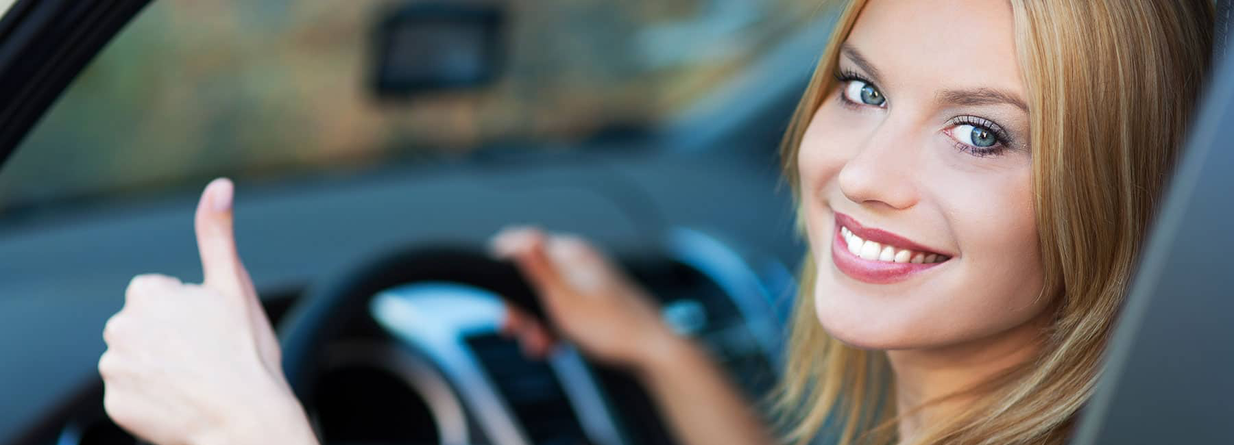 smiling woman in car gives thumbs up