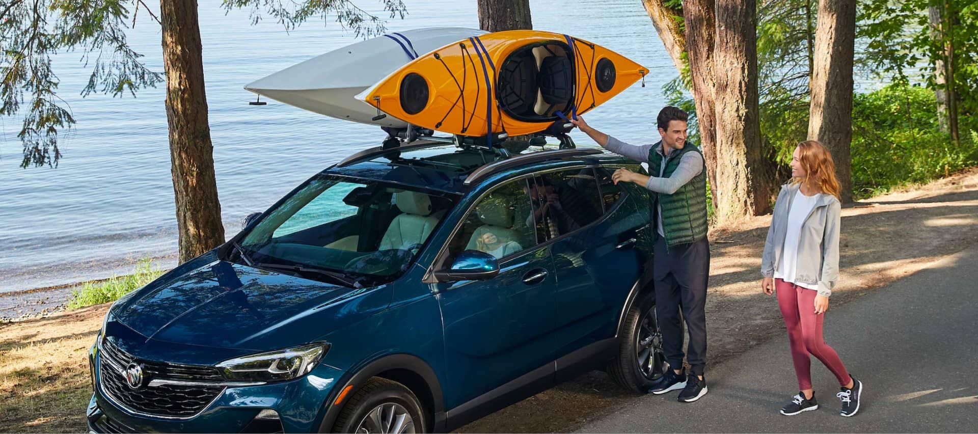 Buick vehicle with people putting kayaks on top