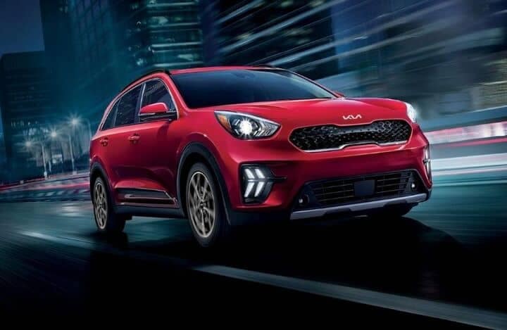 2-Frontview_of_a_Red_2022_Kia_Niro_cruising_on_a_road_o
