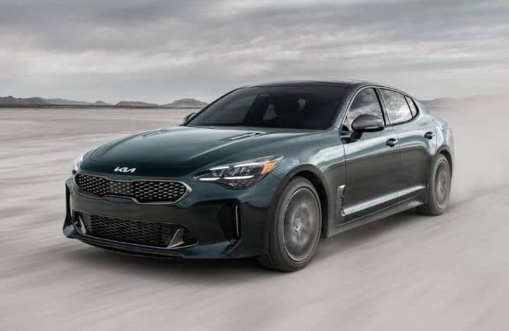 Front view of a green 2022 Kia Stinger cruising on a road