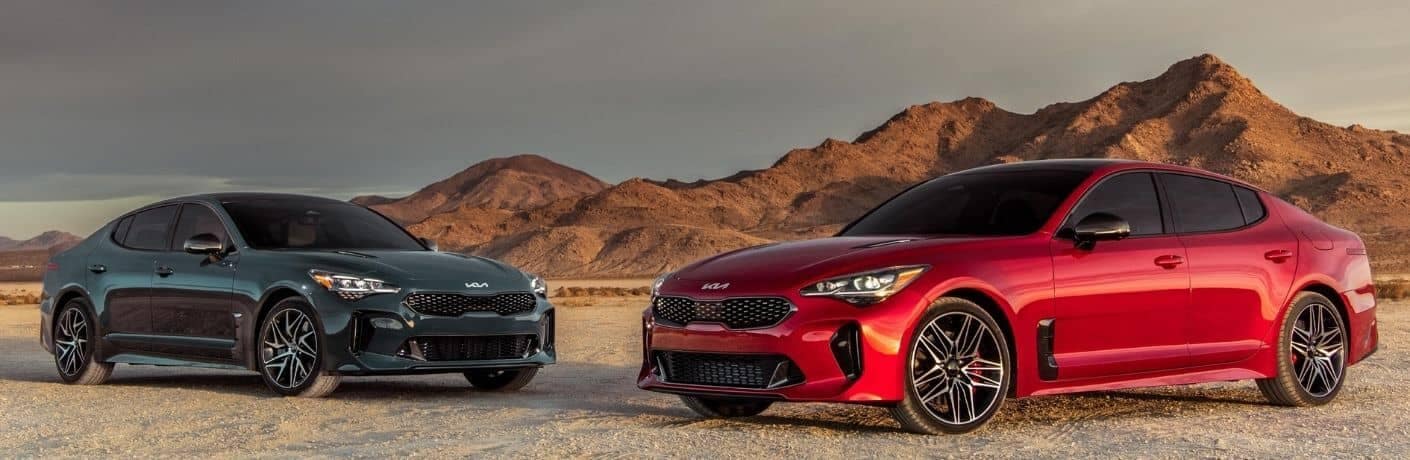 Green and red 2022 Kia Stinger in front of a hill
