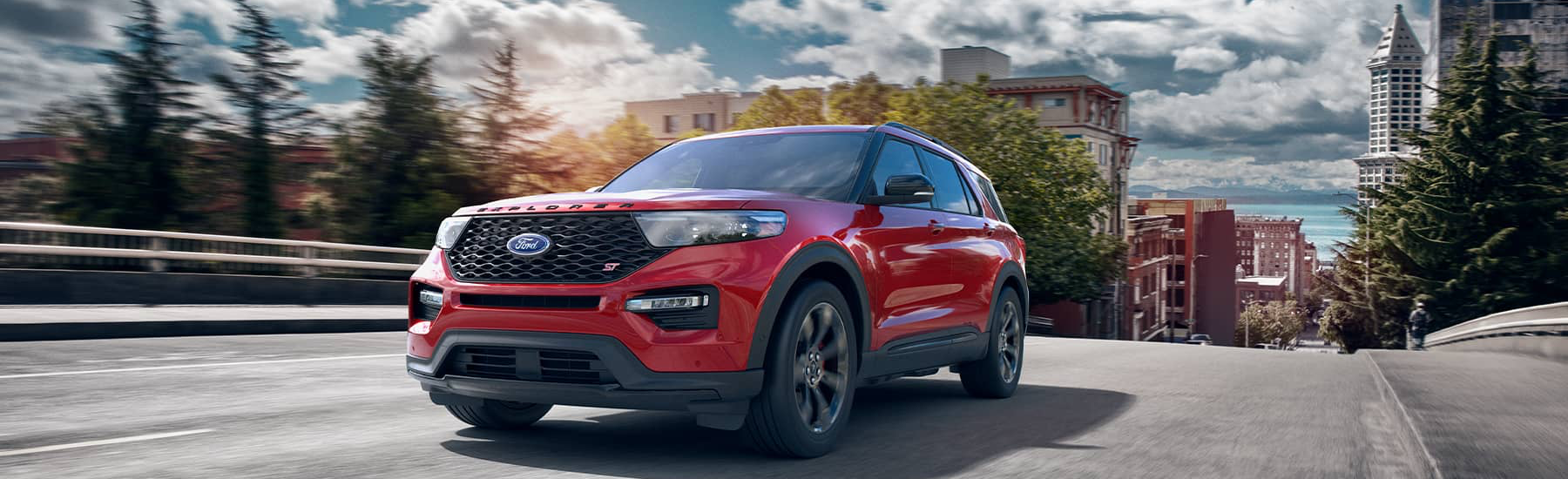 Red 2021 Ford Explorer driving up a hill out of a city