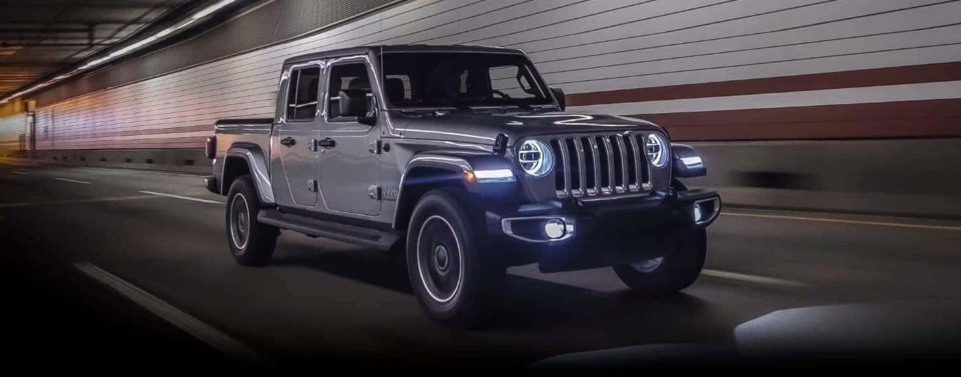 A silver 2023 Jeep Gladiator is shown driving through a tunnel.