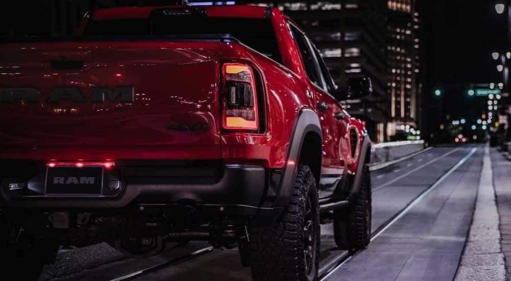 A red 2024 Ram 1500 TRX is shown from the rear on a city street at night.