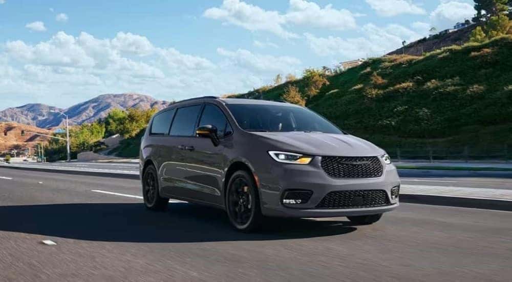 A grey 2024 Chrysler Pacifica is shown driving to a Chrysler dealer.