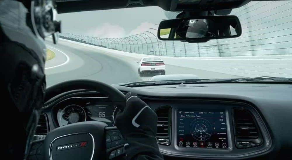 A white 2023 Dodge Challenger is shown from the rear on a race track.
