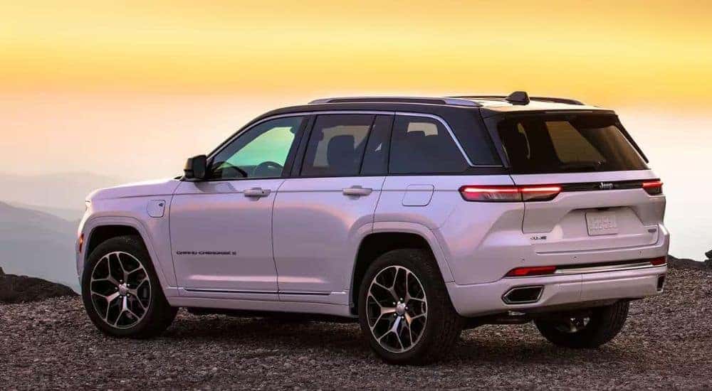 A white 2024 Jeep Grand Cherokee 4xe is shown off-road at sunset.
