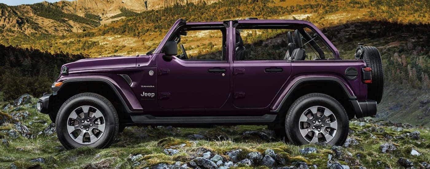 A purple 2023 Jeep Wrangler Sahara Unlimited is shown from the side off-road.