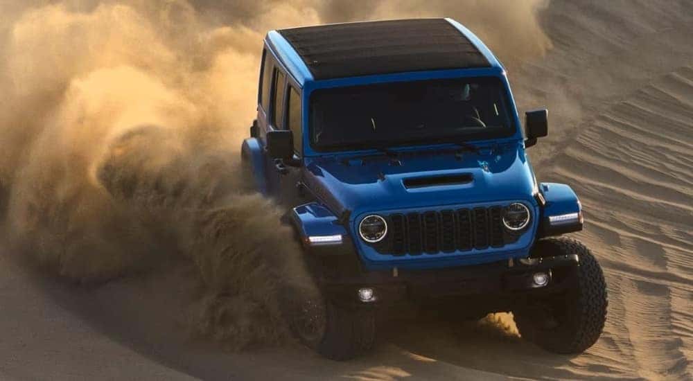 A blue  2024 Jeep Wrangler 392 Rubicon is shown kicking up dust.