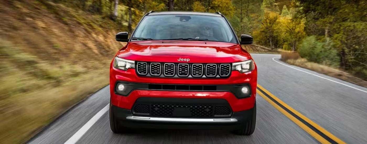 A red 2024 Jeep Compass is shown driving on a highway.