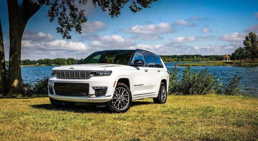 A white 2024 Jeep Grand Cherokee for sale is shown near a lake.