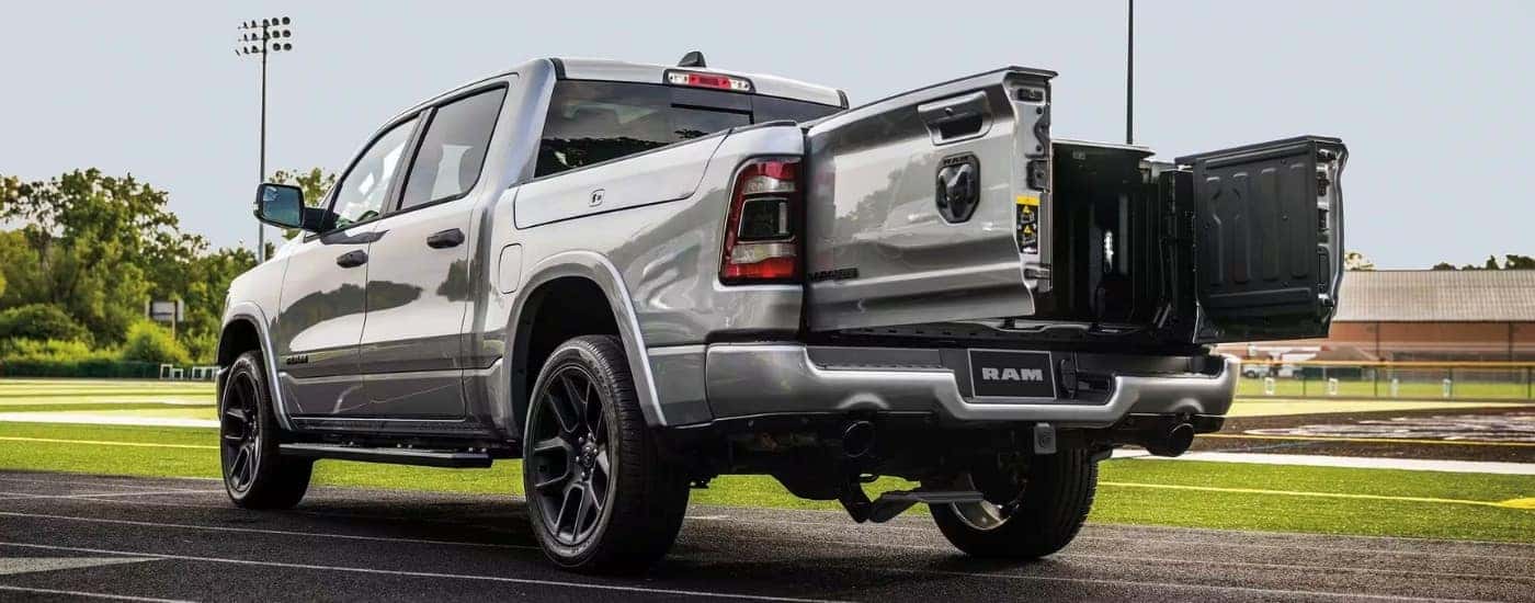 A silver 2024 Ram 1500 is shown from the rear at an angle with the tail-gate open.