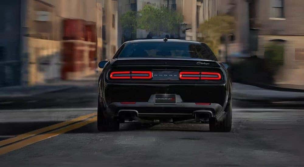 A black 2023 Dodge Challeneger Black Ghost is shown driving on a city street.