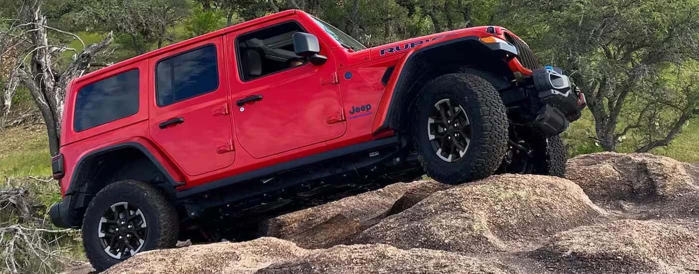 A red 2024 Jeep Wrangler Rubicon 4xe is shown from the side.