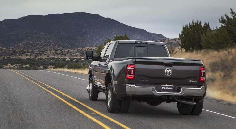 A grey 2023 Ram 3500 Limited is shown driving on an open road.